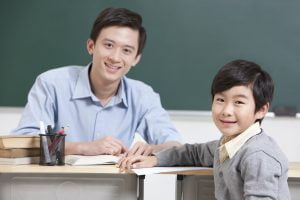 Happy schoolboy and teacher in classroom