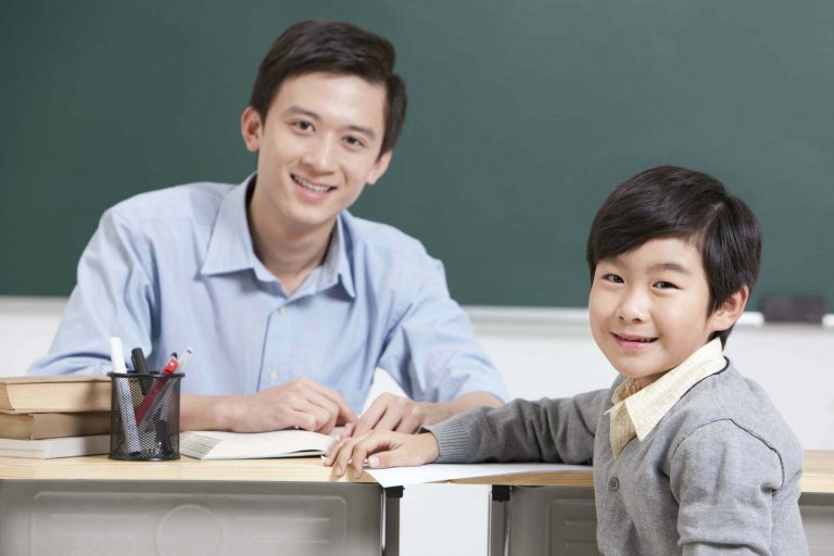 Happy schoolboy and teacher in classroom