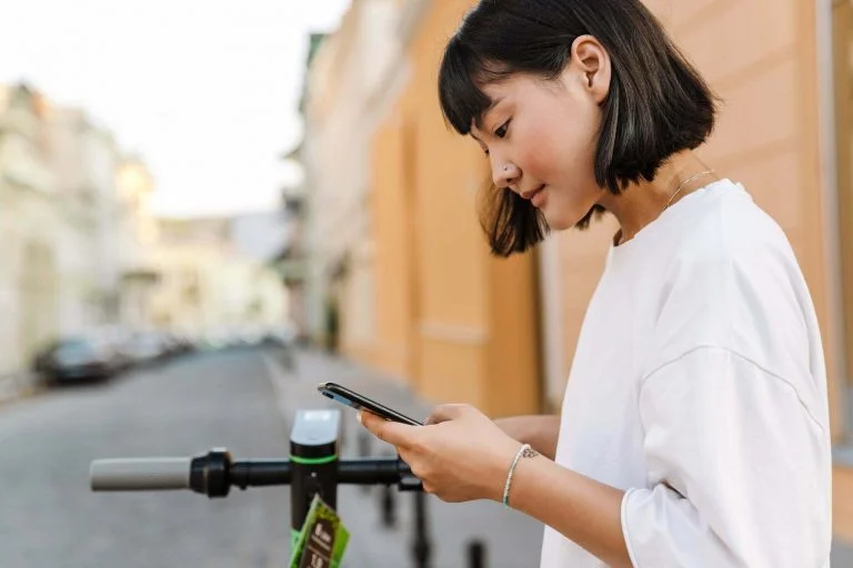 Smiling young asian woman using an app on smartphone
