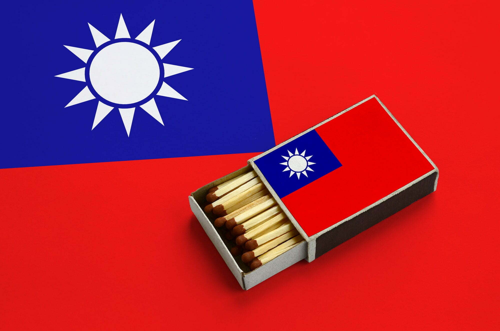 Taiwan flag is shown in an open matchbox, which is filled with matches and lies on a large flag.