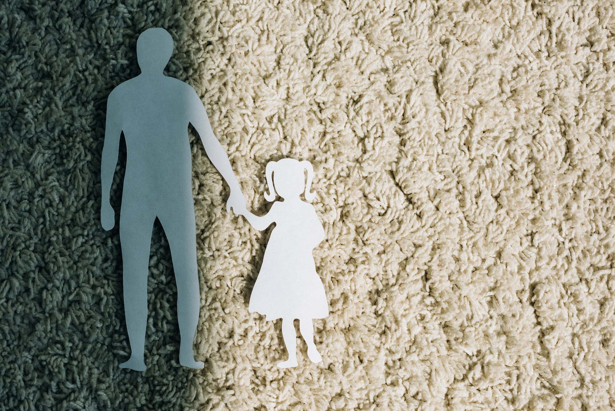 top view of paper figures on carpet, domestic violence concept