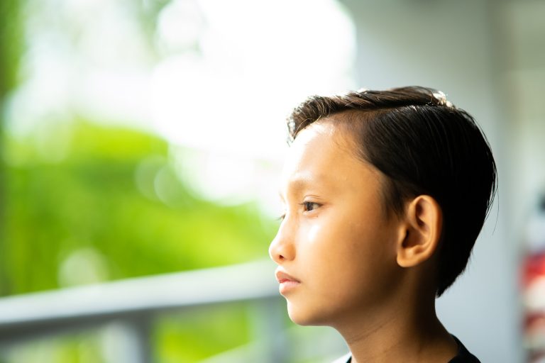 portrait of a young boy looking away near the window. sadness, frustration and cute