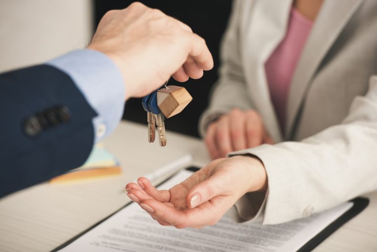 selective focus of realtor giving keys to woman in office