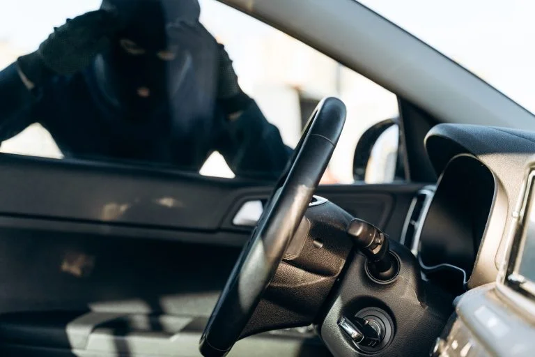 View from the car at the man dressed in black with a balaclava looking at the glass of car