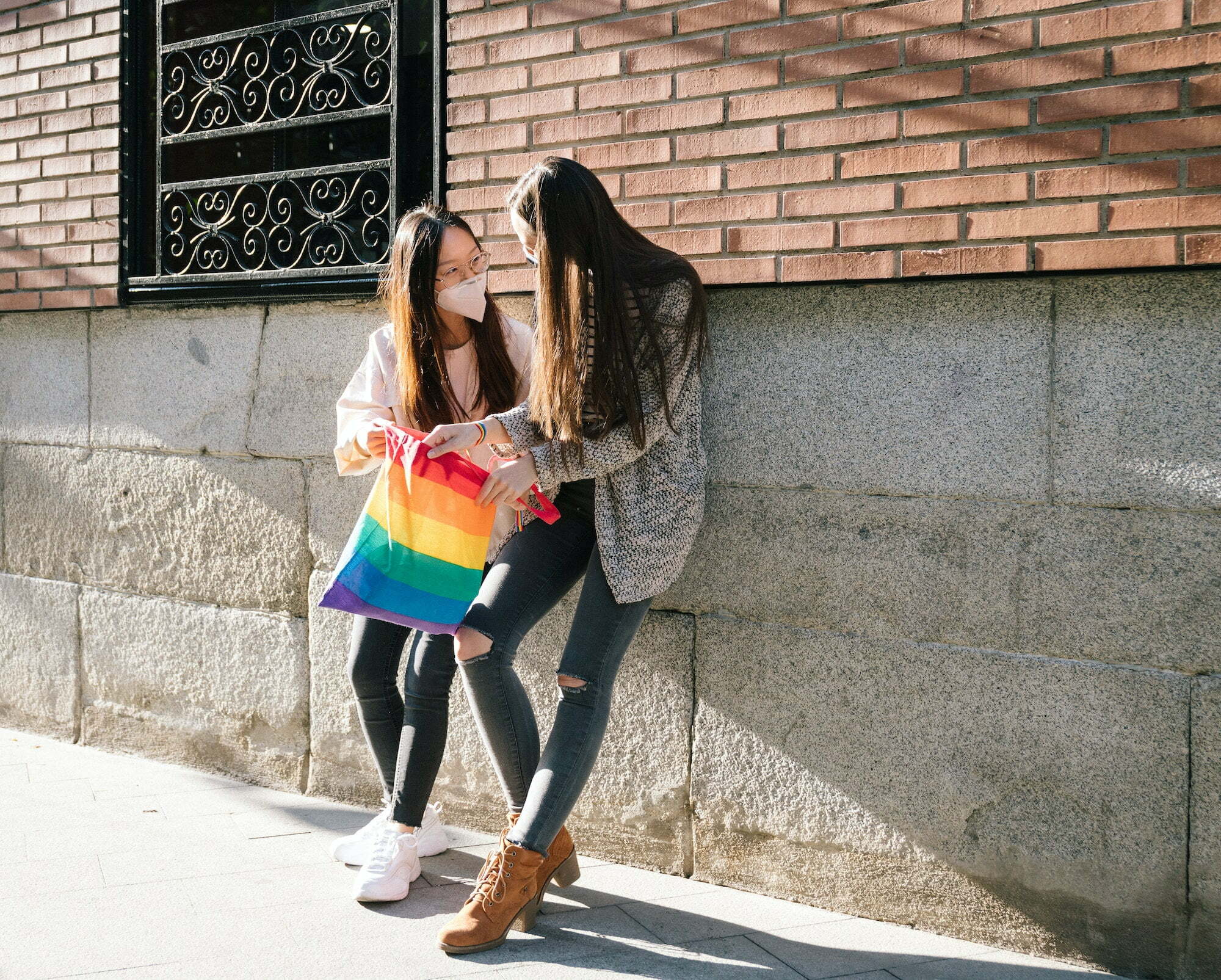 Lesbian couple with rainbow shopping bag in city
