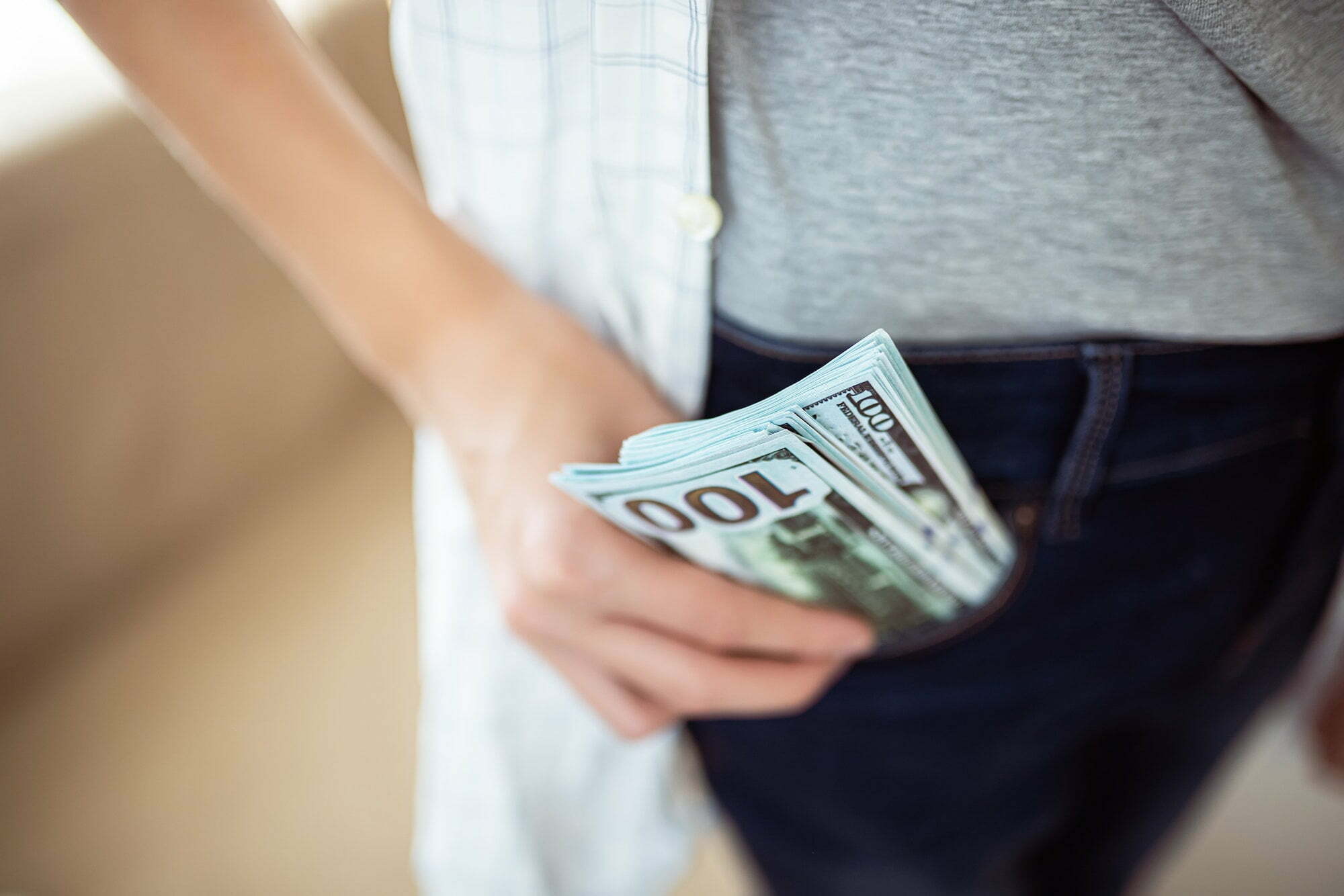 The teenager puts a bundle of dollars in his pocket. Cash salary