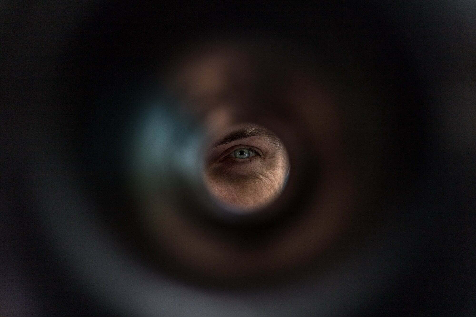 A man's eye looks through the tube. Minimalism. Abstraction