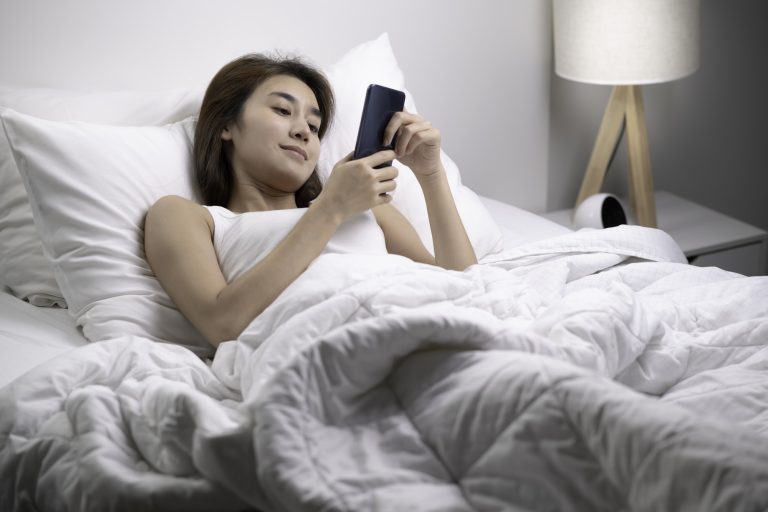 Woman using phone on bed